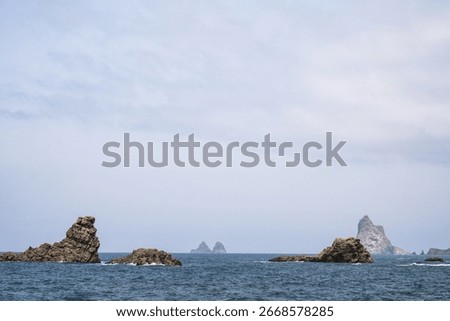 Dramatic coastal rock formations and expansive ocean view under cloudy sky.