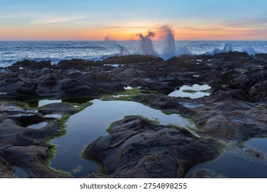 Dramatic coastal sunset scene with waves crashing against rocky shoreline tide-pools. Bean Hollow State Beach, San Mateo Coast, California.