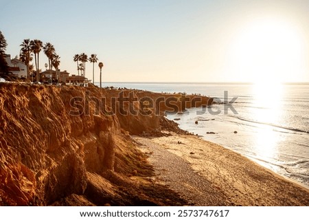 The dramatic coastline of Sunset Cliffs, San Diego, California glows in golden hues as the sun sets, casting warm colors on the rocks