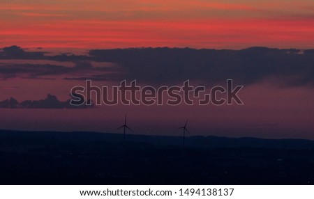 Similar – Landscape shot with wind turbines between fields and four flying cranes in front of a blue sky