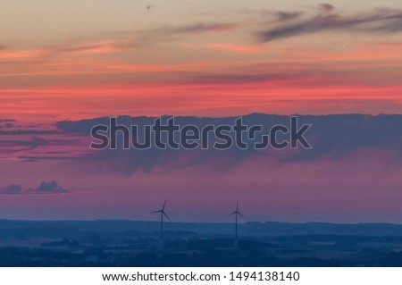 Similar – Landscape shot with wind turbines between fields and four flying cranes in front of a blue sky