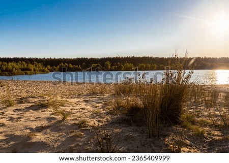 A dramatic and colourful sunset over the Lommelse Sahara (English Lommelse Sahara), a National Park with sand dunes in Belgium with beautiful reflections in the lake of the clouds and natural colours.