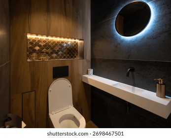 Dramatic compact bathroom with scalloped tile niche circular backlit mirror and wood panel detail