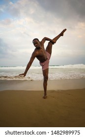 dramatic contemporary dance choreographer doing ballet beach workout . young attractive and athletic afro black American man dancing on sunrise doing performance rehearsal