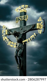 A dramatic crucifix statue against a cloudy sky, featuring golden Hebrew letters and INRI inscription, symbolizing Christian faith.
