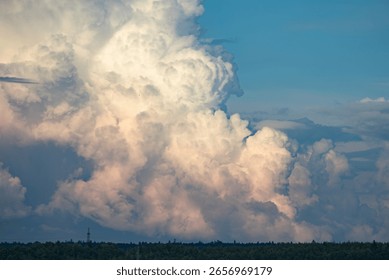 Dramatic cumulonimbus clouds creating a breathtaking spectacle in the sky above a distant forest, illuminated by the warm glow of the setting sun