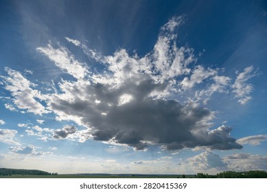 Dramatic cumulus cloud formation over rural horizon with sun rays