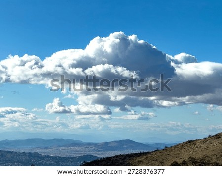 Dramatic cumulus cloud over the Athens basin, panoramic city view from Penteli mountain, Greece. Blue sky