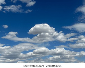 Dramatic cumulus clouds floating across vibrant blue sky creating scenic natural weather atmosphere and peaceful outdoor cloud background