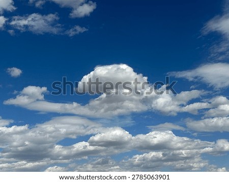Dramatic cumulus clouds floating across vibrant blue sky creating scenic natural weather atmosphere and peaceful outdoor cloud background