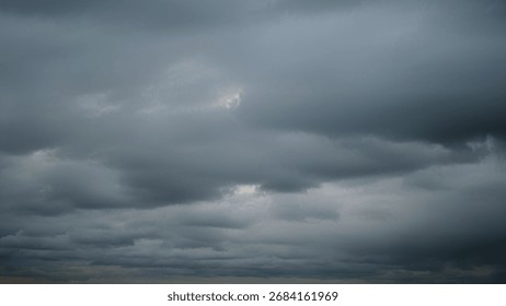 Dramatic dark clouds gather in the sky, creating a moody and stormy atmosphere with shades of gray and hints of fading light, time lapse.