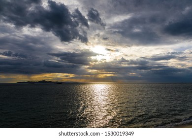 Dramatic dark cloudy sky and sun shining over sea, stormy weather, rays of sun