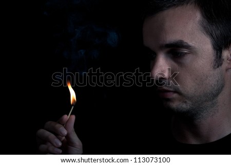 Dramatic dark portrait of man and fire, over black background.