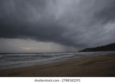 Dramatic dark rain clouds and stormy weather over Kamala beach in Phuket, Thailand.