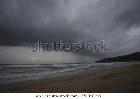 Dramatic dark rain clouds and stormy weather over Kamala beach in Phuket, Thailand.
