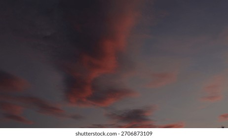 Dramatic, dark sky at twilight featuring wispy, elongated clouds painted in deep shades of pink and red. Captures a moody, abstract, and vibrant sunset or sunrise cloudscape.
