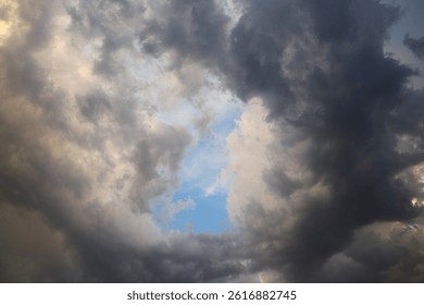 Dramatic dark storm clouds fill the sky, with a small patch of blue visible, creating a moody, atmospheric weather scene - udaipur rajasthan india , april 