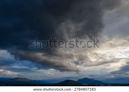 Dramatic dark storm clouds rolling over mountains and valley near Chilliwack, British Columbia, Canada, creating a moody atmosphere.