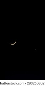 Dramatic deep night sky view with sharp thin crescent moon and planet conjunction in profound darkness