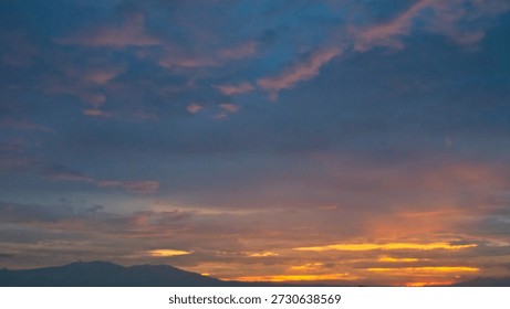 Dramatic deep purple twilight sky with a narrow golden horizon streak framed by dark tree silhouettes.