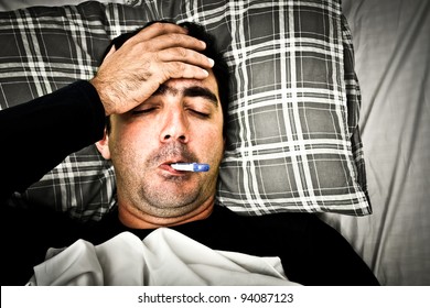 Dramatic Desaturated Image Of A Sick Man Laying In Bed With Fever