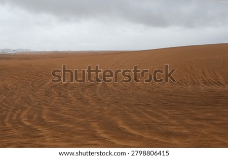 Dramatic desert landscape with rolling sand dunes and storm clouds over the horizon, showcasing the beauty of an arid wilderness environment.