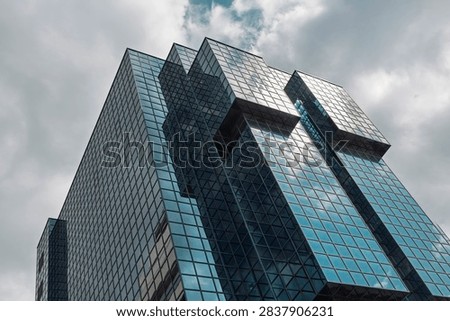 Dramatic diagonal view of a postmodern glass office tower with cantilevered volumes in the City of London against a stormy sky.