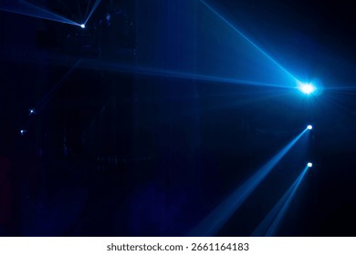 A dramatic display of laser or stage lighting in a dark atmosphere, typically seen at concerts, clubs, or immersive light shows. Blue and purple beams in dark background.
