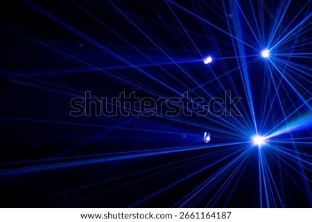 A dramatic display of laser or stage lighting in a dark atmosphere, typically seen at concerts, clubs, or immersive light shows. Blue and purple beams in dark background.