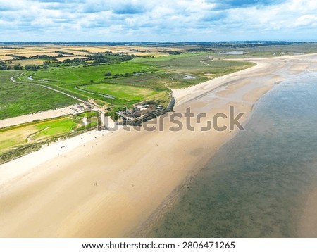 Dramatic drone view of the popular Norfolk, UK beach of Brancaster seen at low tide. The expansive beach can be seen tougher with a Golf Course and Club in the centre of the image.