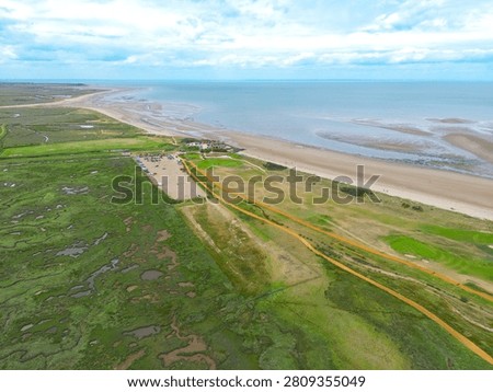 Dramatic drone view of the popular Norfolk, UK beach of Brancaster seen at low tide. The expansive beach can be seen tougher with a Golf Course and Club in the centre of the image.