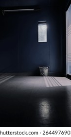 Dramatic empty room with moody shadows and a single bucket under a small window – cinematic minimalist scene in natural light