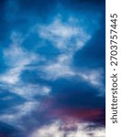 Dramatic evening sky with distant flock of birds;Colorful evening sky with blue and purple clouds and a distant flock of small birds in flight. Atmospheric natural background with soft gradients and m