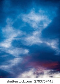 Dramatic evening sky with distant flock of birds;Colorful evening sky with blue and purple clouds and a distant flock of small birds in flight. Atmospheric natural background with soft gradients and m