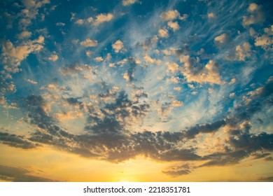 Dramatic evening sky with small clouds. Clouds illuminated by the sun in orange-yellow tones. Romantic twilight landscape. Wide angle panorama.