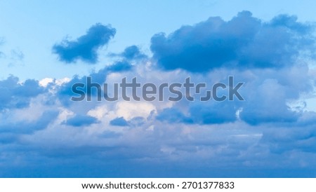 Dramatic evening sky with soft clouds illuminated by cool sunset tones, creating a calm and atmospheric twilight scene