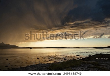 Dramatic evening storm clouds at stunning evening over the beach at Mjelle in Northern Norway pouring rain over the bay