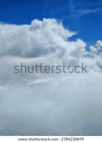 A dramatic and expansive sky dominated by thick, billowy white clouds in motion, creating a serene and vast natural landscape.