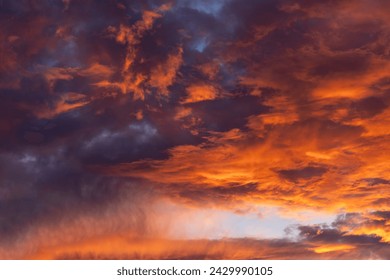 Dramatic fiery cloudy evening sky at sunset, clouds of bright colors in twilight