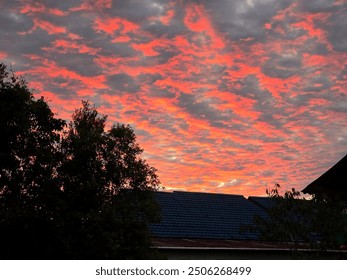 Dramatic Fiery Sunset with Vibrant Clouds Over Rooftops