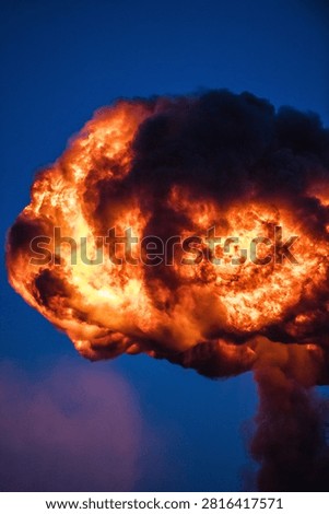Dramatic fireball explosion creating intense flames, smoke and glowing light during a pyrotechnic demonstration or special effects performance.