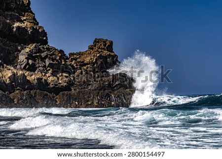 Dramatic footage of powerful Atlantic Ocean waves crashing against the rocky coastline of Tenerife, Canary Islands. Rough sea conditions, dangerous surf, and strong currents make swimming unsafe near the black volcanic sand beach. Natural forces, coastal hazards, extreme weather, and the rugged beauty of the volcanic shoreline create a striking travel and nature scen