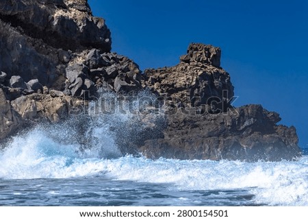 Dramatic footage of powerful Atlantic Ocean waves crashing against the rocky coastline of Tenerife, Canary Islands. Rough sea conditions, dangerous surf, and strong currents make swimming unsafe near the black volcanic sand beach. Natural forces, coastal hazards, extreme weather, and the rugged beauty of the volcanic shoreline create a striking travel and nature scen