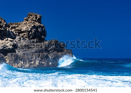 Dramatic footage of powerful Atlantic Ocean waves crashing against the rocky coastline of Tenerife, Canary Islands. Rough sea conditions, dangerous surf, and strong currents make swimming unsafe near the black volcanic sand beach. Natural forces, coastal hazards, extreme weather, and the rugged beauty of the volcanic shoreline create a striking travel and nature scen