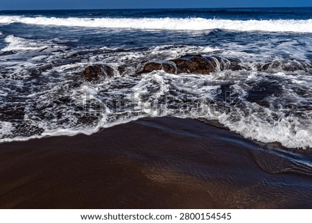 Dramatic footage of powerful Atlantic Ocean waves crashing against the rocky coastline of Tenerife, Canary Islands. Rough sea conditions, dangerous surf, and strong currents make swimming unsafe near the black volcanic sand beach. Natural forces, coastal hazards, extreme weather, and the rugged beauty of the volcanic shoreline create a striking travel and nature scen