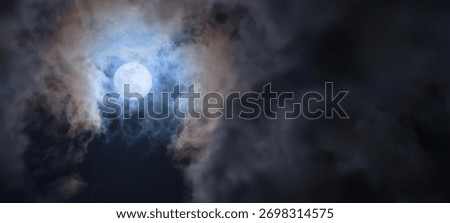 Dramatic full moon glowing through swirling night clouds, with visible lunar surface details. Atmospheric and ethereal celestial scene perfect for astronomy or artistic use.