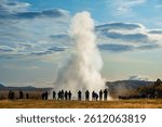 A dramatic geyser Strokkur eruption captured with a crowd of onlookers enjoying the impressive natural display. Golden Circle attraction.