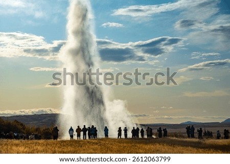 A dramatic geyser Strokkur eruption captured with a crowd of onlookers enjoying the impressive natural display. Golden Circle attraction.