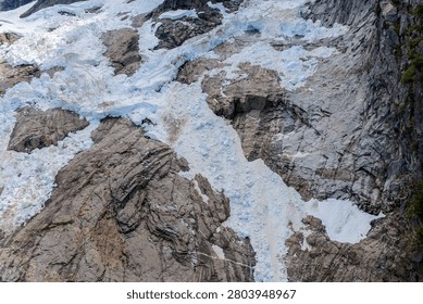 A dramatic glacier icefall cascading over bare rock on a mountain face, British Columbia, Canada landscape.