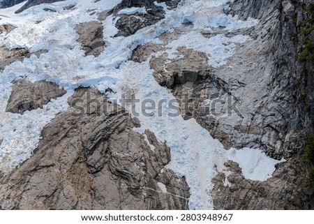 A dramatic glacier icefall cascading over bare rock on a mountain face, British Columbia, Canada landscape.